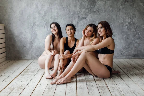 Vriendschap, schoonheid, lichaam positief en mensen concept - groep van gelukkige vrouwen verschillend in ondergoed over grijze achtergrond — Stockfoto