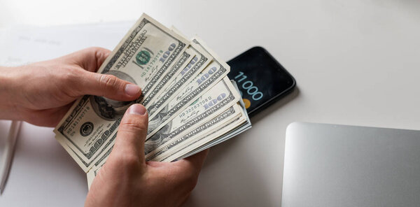 Мужские руки, считая долларовые купюры или оплачивая наличными на денежном фоне. Концепция инвестиций, успех, финансовые перспективы