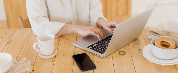 Zbliżenie dziewczyny pracującej na laptopie, wpisującej tekst. Na stole jest laptop i telefon. Praca jako wolny strzelec lub programista — Zdjęcie stockowe