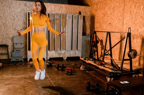 Una chica deportiva salta en una cuerda en un gimnasio moderno. fotos en movimiento — Foto de Stock