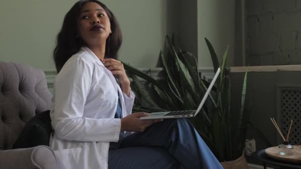 Vrouwelijke Afrikaanse arts in gesprek op videoconferentie. Virtuele therapeut advies tijdens online afspraak op laptop thuis. Telegeneeskundechat, vergadering telegezondheid — Stockvideo
