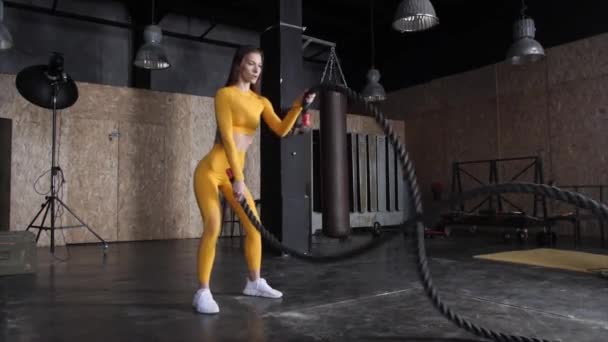 Спортивна молода жінка робить деякі кросфітні вправи з мотузкою в приміщенні. Повільний рух — стокове відео