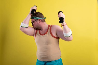 Komik şişman adam spora gider. Dambıl pazısı egzersizi yapar mı?