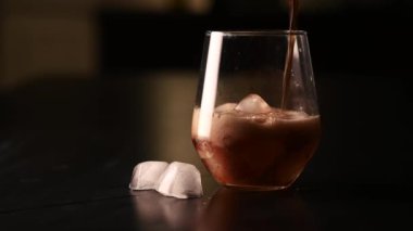 Karanlık bir arka planda buzlu soda dolu bir bardakta