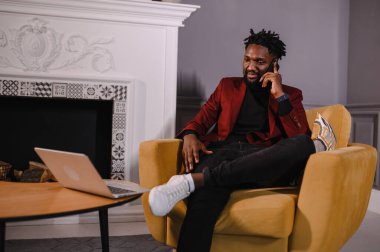 Gülümseyen milenyum Afrikalı Amerikalı sıradan bir adam uygulamalarla çalışıyor ya da bilgisayarla iletişim kuruyor.