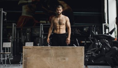 Gözleri kapalı yakışıklı vücut geliştirici spor salonunda balyoz egzersizi yaptıktan sonra dinleniyor. Tam uzunlukta kenar görünüm fotoğrafı