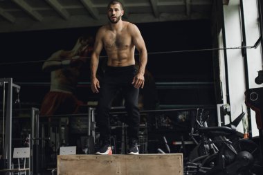 Gözleri kapalı yakışıklı vücut geliştirici spor salonunda balyoz egzersizi yaptıktan sonra dinleniyor. Tam uzunlukta kenar görünüm fotoğrafı