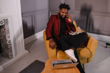 Gülümseyen milenyum Afrikalı Amerikalı sıradan bir adam uygulamalarla çalışıyor ya da bilgisayarla iletişim kuruyor.