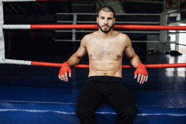 Dövüşçü Kum Torbasıyla Tekme Antrenmanı yapıyor. Koyu arkaplanda tekme, kum torbası. Spor salonunda siyah kum torbası tartılır.