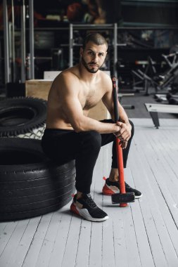 Gözleri kapalı yakışıklı vücut geliştirici spor salonunda balyoz egzersizi yaptıktan sonra dinleniyor. Tam uzunlukta kenar görünüm fotoğrafı