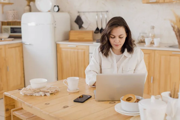 Gelukkig jong mooi vrouw met behulp van laptop in haar modern helder appartement — Stockfoto