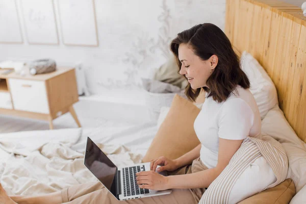 Vrouw ontspannen op bed met behulp van laptop computer voor video bellen in moderne flat — Stockfoto