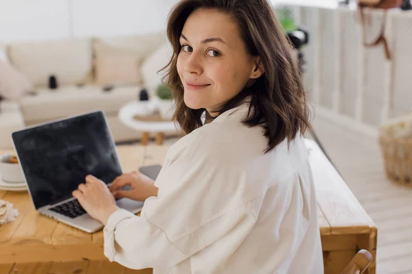 Gelukkig jong mooi vrouw met behulp van laptop in haar modern helder appartement — Stockfoto