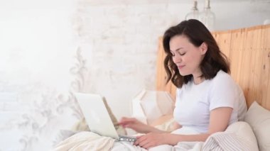 Yatakta Dinlenen Kadın Bilgisayarı kullanarak Modern Daire 'de Video Görüşmesi Yapıyor