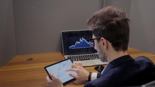 Trader yang sukses menganalisis saham dan pasar saham menggunakan laptop dan tablet. perdagangan saham, naiknya dan jatuhnya pasar saham — Stok Video