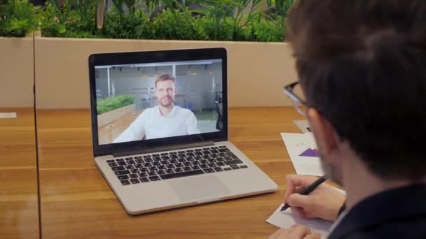 Por encima de la vista del hombro de los trabajadores masculinos tienen webcam conferencia virtual digital. Empresario hablar hablar en videollamada con el gerente. Concepto de reunión en línea. — Vídeos de Stock