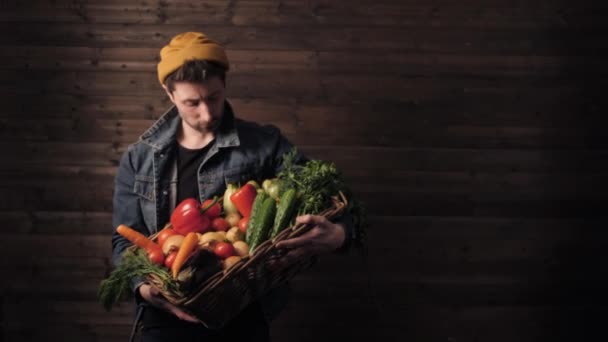 Agricultor joven sostiene una cesta de mimbre con verduras orgánicas frescas. pequeña empresa. Captura de estudio — Vídeos de Stock