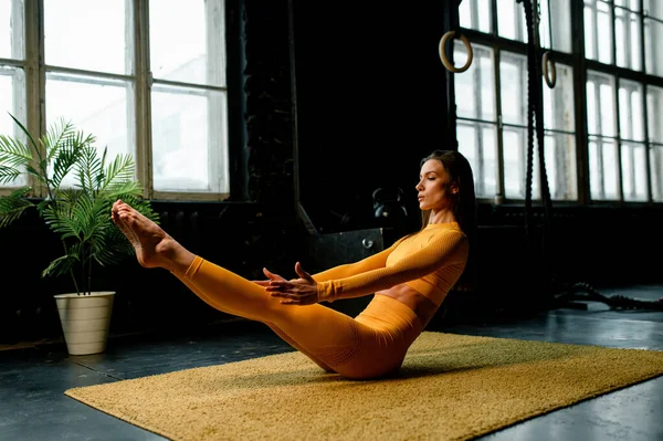 Sarı spor kıyafetli güzel kız yoga yapıyor, doğru nefes alıyor. Modern spor salonu — Stok fotoğraf