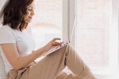 Çekici bir kadın rahat oturma odasındaki masada dizüstü bilgisayarla çalışıyor. İş kadını iş yerinde oturur, bilgisayardan mesaj atar, yoğun bir gün geçirir.