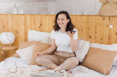 Parlak dairesi olan genç ve çekici bir kız, dizüstü bilgisayar kullanarak sabahtan zevk alıyor. Sosyal ağları kontrol eder