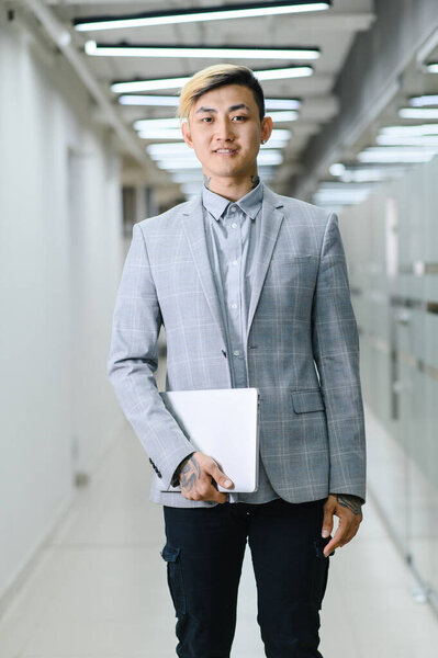 Счастливый молодой человек сидит в современном офисе и смотрит в камеру с улыбкой