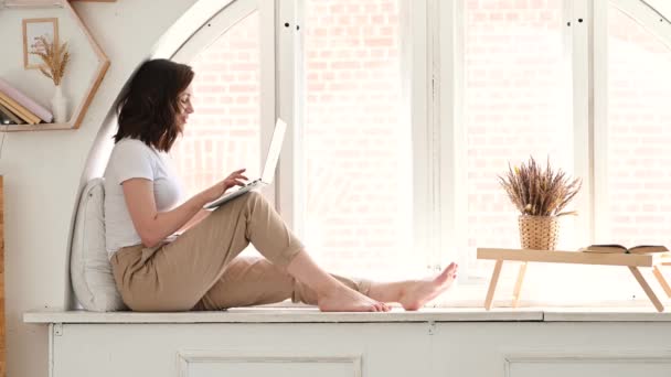 Séduisante femme travaillant sur ordinateur portable assis au bureau dans le salon confortable. Femme d'affaires assis sur le lieu de travail, texte sur l'ordinateur ayant occupé journée fructueuse à la maison — Video