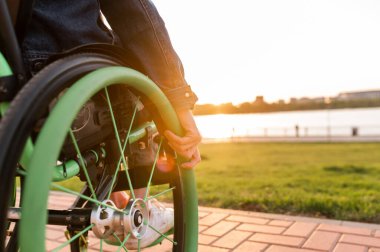 Engelli bir adam tekerlekli sandalyede oturuyor. Ellerini direksiyonda tutuyor..