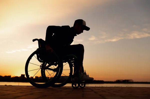 Силуэт человека в инвалидной коляске на фоне заката — стоковое фото