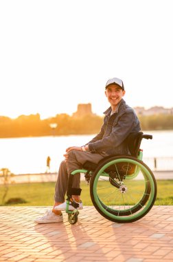  Tekerlekli sandalyedeki engelli genç adam. Gün batımında tekerlekli sandalyede yürüyüş yapan engelli.