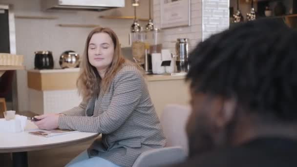 Egy afro-amerikai férfi és egy európai külsejű lány találkoznak egy étteremben. Egy beszélgetés két ember között. — Stock videók