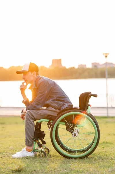 Инвалид, сидящий на инвалидной коляске и наслаждающийся прогулкой на открытом воздухе — стоковое фото