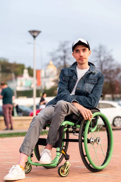Mladý muž na invalidním vozíku, procházející se po městě, užívající si západ slunce — Stock fotografie