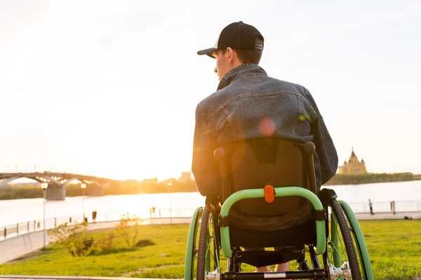 Молодой человек в инвалидной коляске, гуляющий по городу, наслаждающийся закатом — стоковое фото