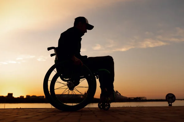 Силуэт инвалида в инвалидной коляске на фоне заката — стоковое фото