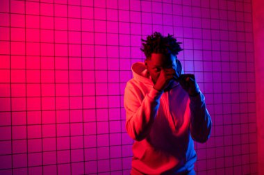 Neon arka planda kapüşonlu Afro-Amerikan bir adamın portresi. Kırmızı-mavi arkaplan.