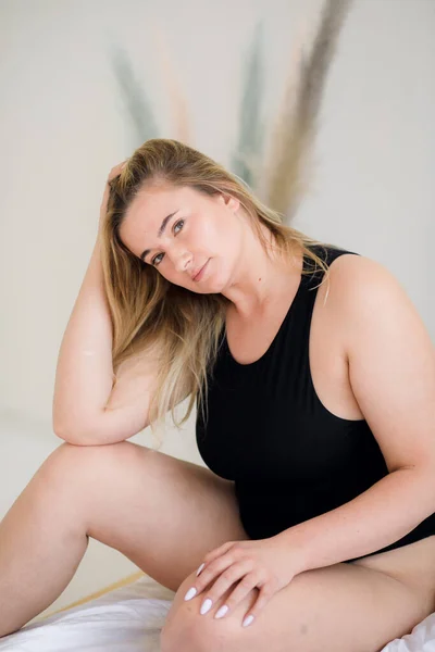 Schöne übergewichtige Frau im schwarzen Badeanzug auf grauem Hintergrund — Stockfoto