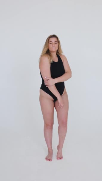 Beautiful overweight woman in black swimsuit on grey background — Stock Video