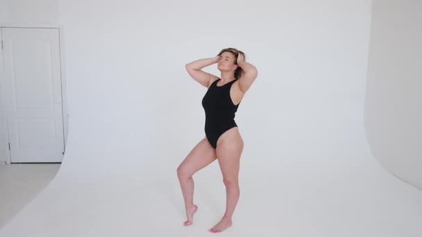 Beautiful overweight woman in black swimsuit on grey background — Stock Video