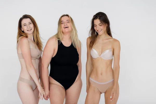 Souriant filles multiculturelles en lingerie câlins tout en posant à la caméra isolé sur blanc, concept de positivité du corps — Photo