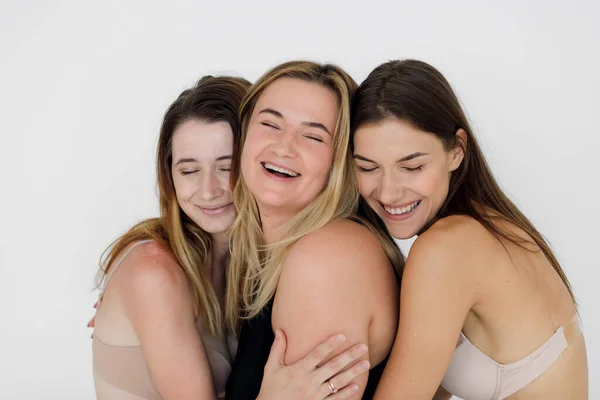 Amizade, beleza, corpo positivo e conceito de pessoas - grupo de mulheres felizes diferentes em roupa interior branca sobre fundo rosa — Fotografia de Stock