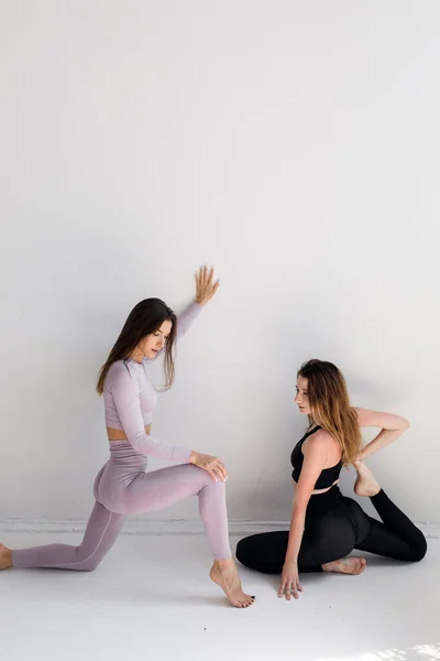 Dos chicas deportivas posando aisladas sobre un fondo blanco. Modelo de fitness mujer en estudio con espacio de copia — Foto de Stock