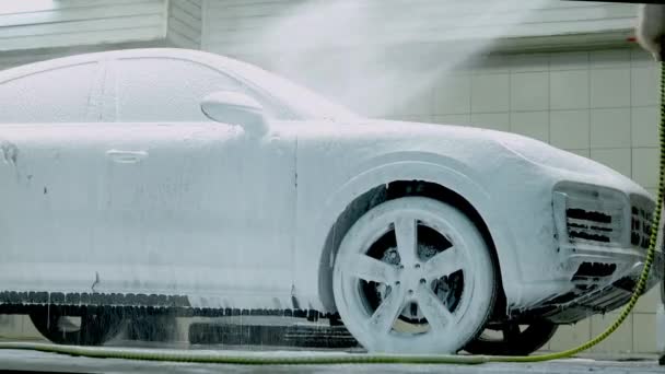 Carro de limpeza com shampoo de espuma de neve branca. Pulverizando espuma de neve branca no capô do carro e farol. Pulverizando espuma de xampu de carro para capuz de carro — Vídeo de Stock