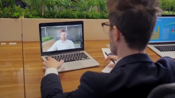 Przez ramię widok męskiego pracownika mają kamerę internetową wirtualnej konferencji. Biznesmen rozmawia przez wideo rozmowę z menadżerem. Koncepcja spotkania internetowego. — Wideo stockowe