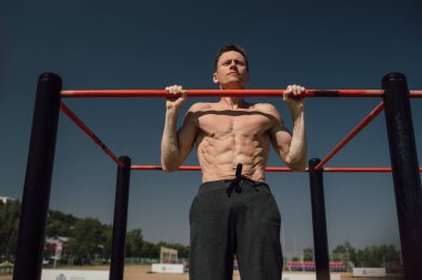 Sokakta yatay çubukla çalışan kaslı bir adam.