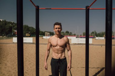 yakışıklı genç adam sokak egzersiz sahilde bir aydınlık yaz günü yapıyor.