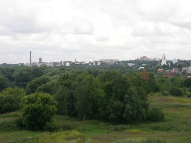 Tepeden şehire yeşil ağaçlar ve beyaz kilise kubbeleri var.