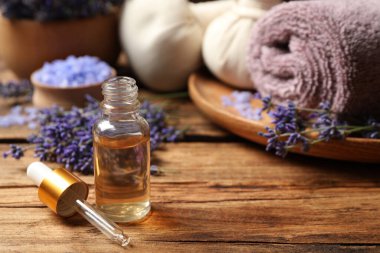 Ahşap masanın üzerinde gerekli yağ ve lavanta çiçekleri olan kompozisyon. Metin için boşluk