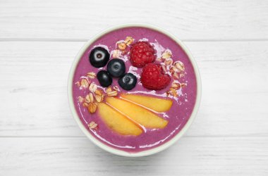 Şeftali dilimleri ve beyaz ahşap masada yulaf ezmeli nefis acai smoothie.