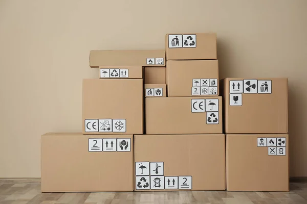 Cajas Cartón Con Diferentes Símbolos Embalaje Suelo Cerca Pared Beige — Foto de Stock