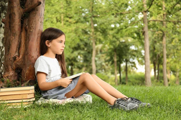 Linda Niña Leyendo Libro Sobre Hierba Verde Cerca Del Árbol — Foto de Stock